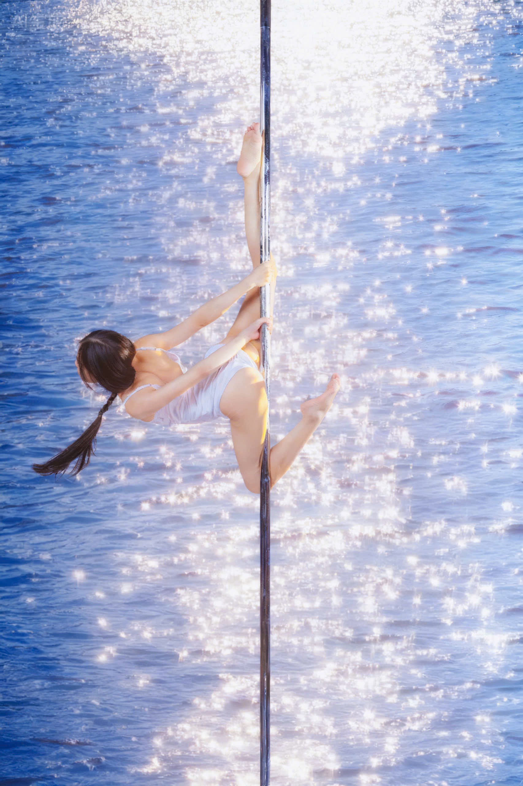 Soft, ethereal pole pose over sparkling water showing flow and grace
